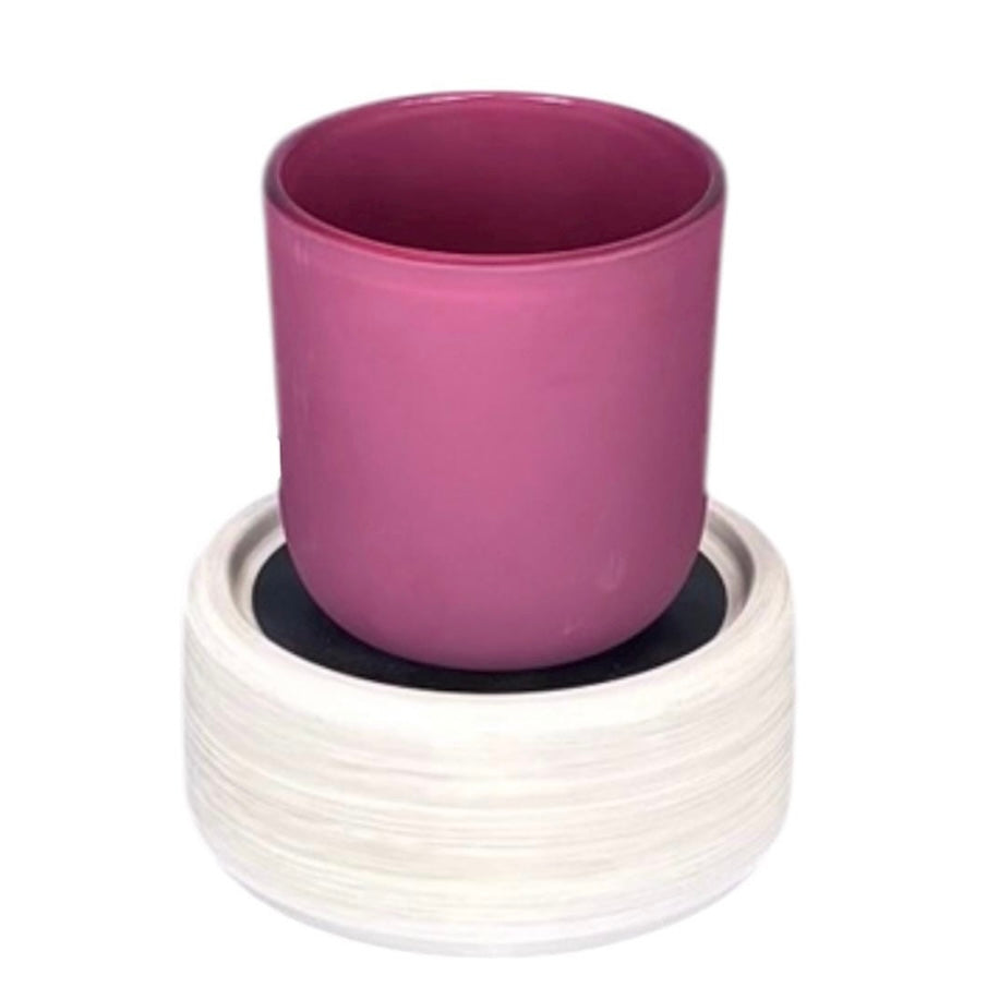 White base of a wax warmer with a candle on top with a plain background