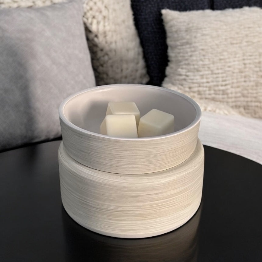 White ceramic wax warmer on a dark surface, with soft lighting